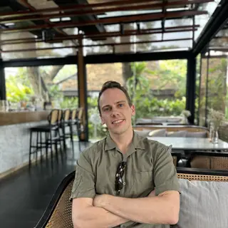 Ambroise Debret, bras croisés et souriant, dans un café de Chiang Mai